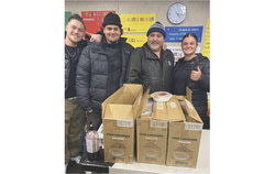 De gauche à droite : deux employés de Patate Lou Lou en compagnie du propriétaire, Laurent Lamirande, et de Jade Fahey, intervenante à la halte-chaleur Réhabex du site Guertin, avec les boîtes de dons de repas (30 janvier 2025). Photo : Gracieuseté d’Annie Castonguay